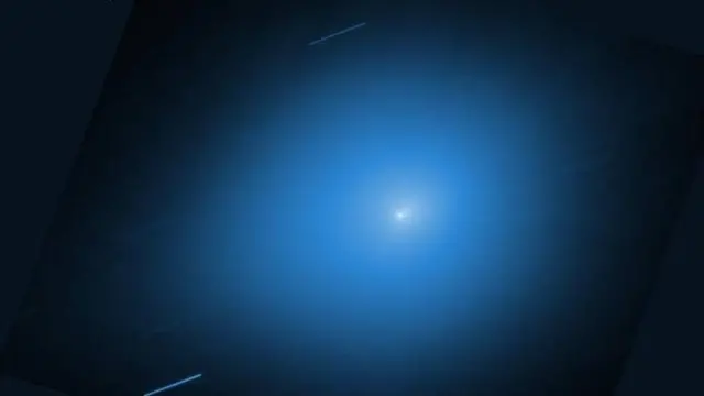 Image of Comet 3I/ATLAS showing a bright spot with a central trail against a light blue background