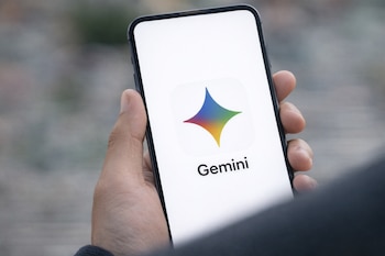 A hand holds a mobile phone with a screen showing the Google Gemini logo.